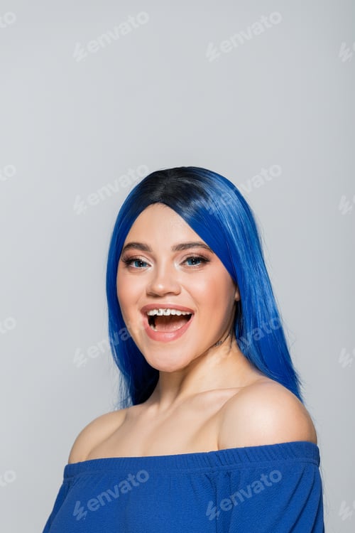 Preview: excitement and youth, tattooed woman with blue eyes and dyed hair smiling on grey background