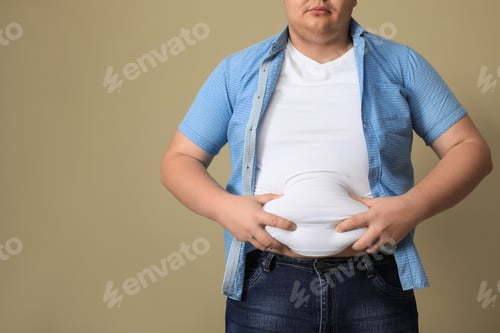 Preview: Overweight man in tight t-shirt on beige background, closeup. Space for text