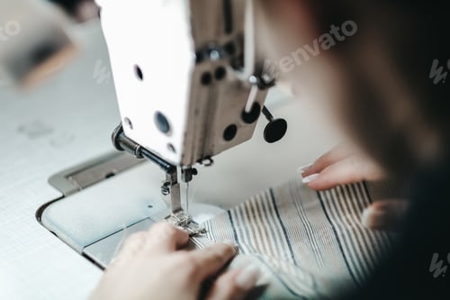 Preview: Shallow focus shot of a female sewing with a sewing machine