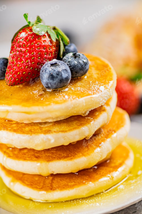 Preview: Pancakes with honey and berries on a plate.