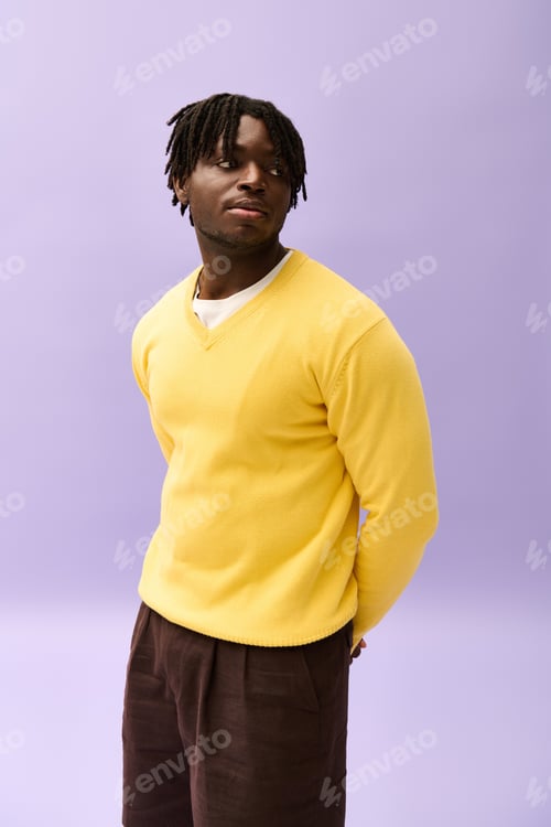 Preview: Handsome young man dressed in stylish yellow sweater poses against a pastel backdrop