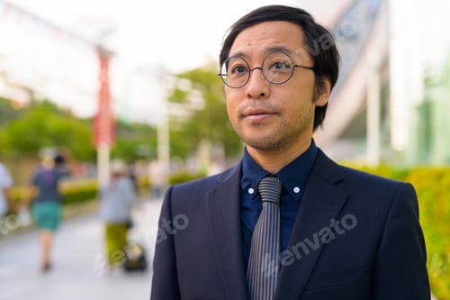 Preview: Face of Asian businessman thinking with nature in the city outdoors