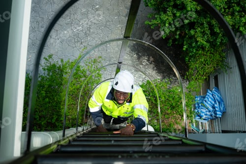 Preview: Technician climbs a ladder to the rooftop to check the installation of solar panels
