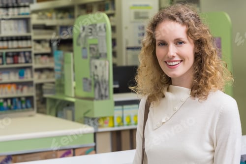 Preview: Female shopper smiling at pharmacy counter with medicine bottles and computer monitor, copy space
