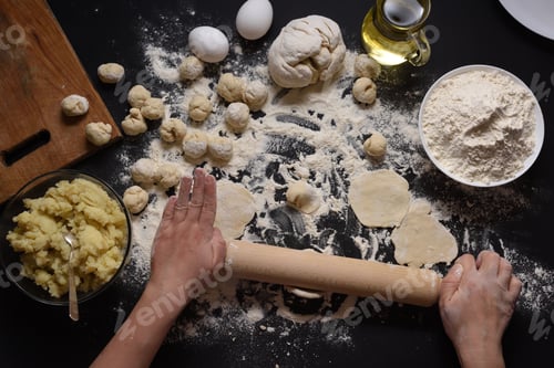 Preview: Woman sculpts dumplings with handmade potatoes on a black background. Shot from the top angle.