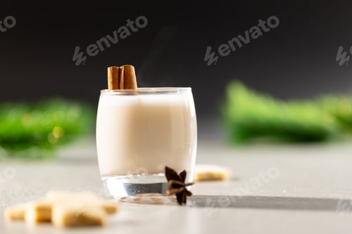 Preview: Image of glass of milk with cinnamon and christmas decorations with copy space on grey