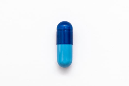 Preview: Close-up one blue powder soft capsule pill isolated on white. medicine supplement vitamin