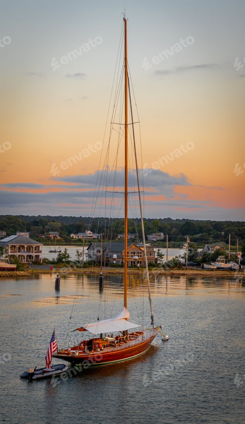 Preview: Vertical shot of a sailboat in the ocean in daylight against the orang sky in Martha's vineyard
