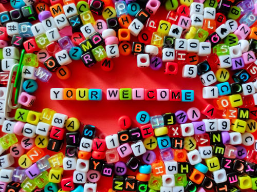 Preview: Colorful dice with word YOUR WELCOME on a red background