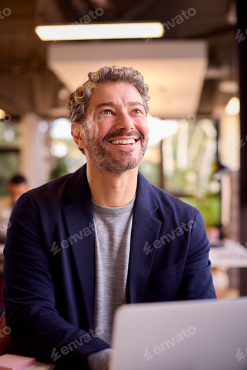 Preview: Mature Businessman Working On Laptop At Desk In Office