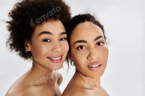 Preview: Two women with radiant smiles posing closely together against a soft, light background