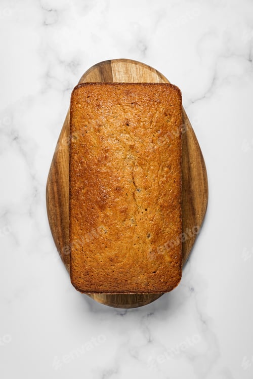 Preview: Close-up of banana bread loaf on a wooden board on marble background
