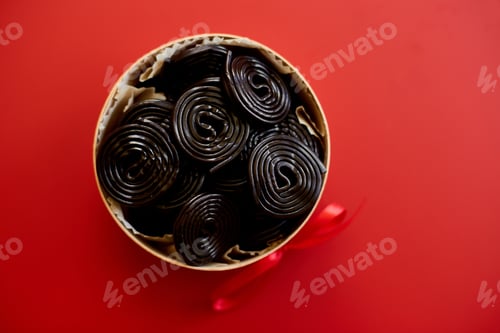Preview: Tasty black liquorice candies in present box on red background