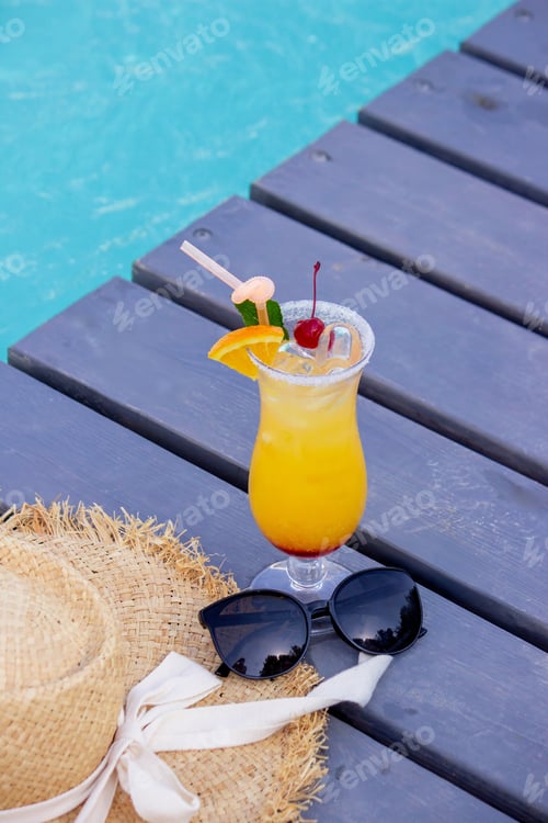Preview: A nice cocktail, hat and sunglasses by the pool
