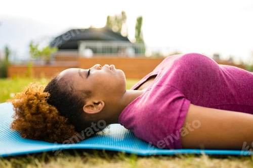 Preview: Happy young african american woman trainer with short curly hair ready for yoga time outdoors