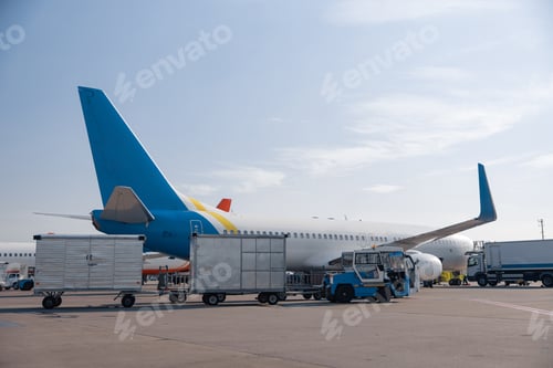 Preview: Airfield tractors near big modern airplane ready for boarding in airport hub on a daytime