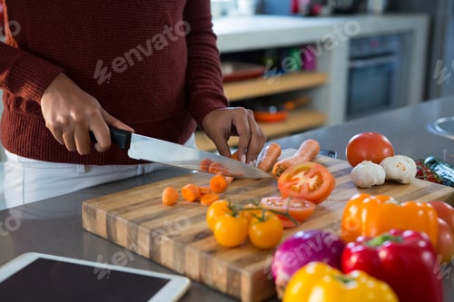 Preview: Mid section of woman cutting vegetables