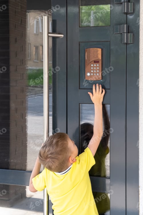 Preview: A little boy reaches for the bell to ring the doorbell, view from the back. A child standing near