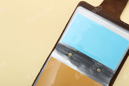 Preview: Leather business card holder with colorful cards on beige background, top view