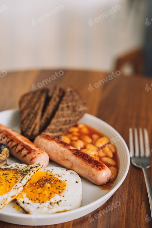 Preview: Fried eggs with sausages and rye bread on a white plate with a fork