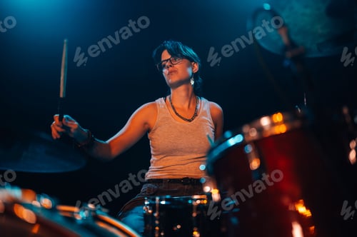 Preview: Female drummer performing energetically on stage with drumsticks and cymbal