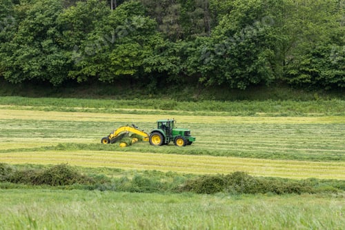 Preview: Rural scene of a tractor and machinery harvesting cut grass