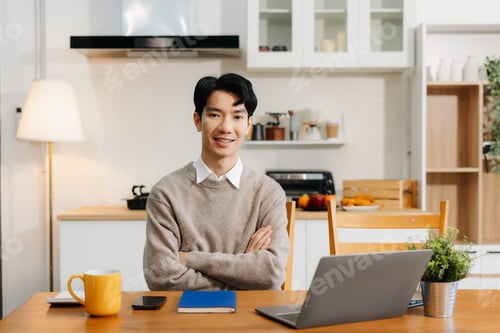 Preview: Happy male enjoying work sitting in the kitchen, looking to camera.