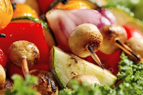 Preview: vegetarian skewers with dry herbs on wooden skewers of zucchini tomato onion mushrooms on a plate