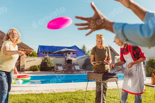 Preview: Senior people having fun playing outdoor games and making barbecue in the backyard