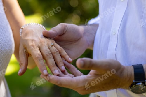 Preview: Showing engagement ring, senior bride and groom holding hands outdoors, at outdoor wedding