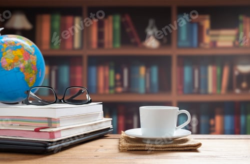 Preview: White coffee cup, eyeglasses with book stacked and black laptop on wooden table in home office room
