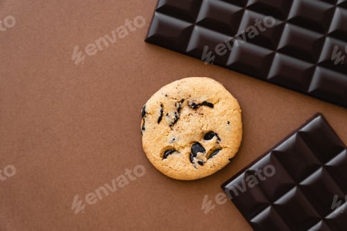 Preview: Top view of cookie near dark chocolate bars on brown background