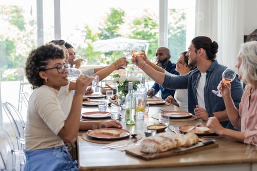 Preview: Friends and family toasting with wine glasses at elegant dining table celebration