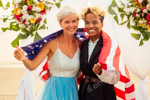 Preview: african american female groom in black suit and happy caucasian blonde bride l