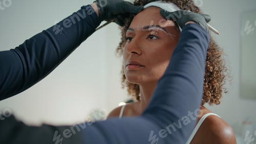 Preview: Cosmetologist shaping woman brows in beauty salon closeup. Curly girl visiting