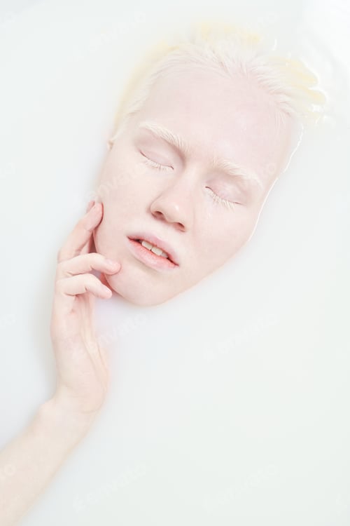 Preview: Above view of peaceful albino girl touching her face while taking bath