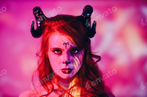 Preview: Woman makeup zodiac signs of Aries sign horoscope. Girl with horns on head in neon light.