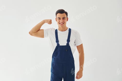 Preview: Male worker in blue uniform standing inside of studio against white background