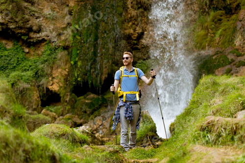 Preview: Young hiker stopped beside a mountain waterfall to rest