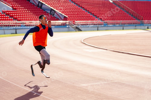 Preview: Asian para-athletes with prosthetic blades sprint on a running track at stadium.