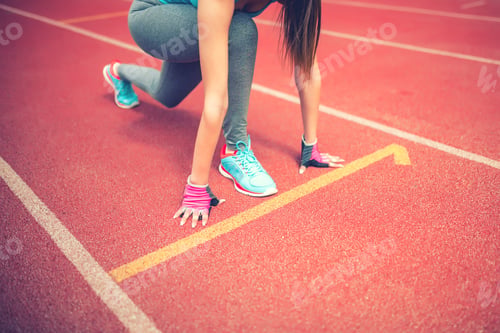 Preview: athlete on starting blocks at stadium track preparing for a sprint. Fitness, healthy lifestyle