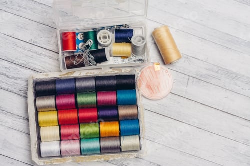 Preview: ball of multicolored threads in a box and sewing supplies needles and pins on a wooden table