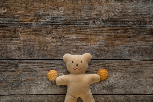 Preview: Adorable teddy bear holding cookies on wooden table. Space for text