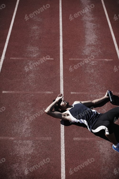 Preview: Life in the fast lane is tiring. A young runner lying down on the tartan track.