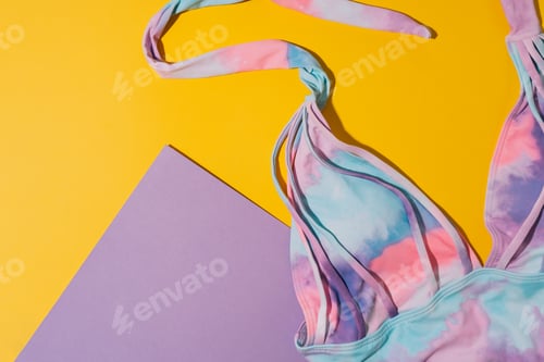 Preview: Multi-colored swimsuit with purple sheet of paper on yellow background