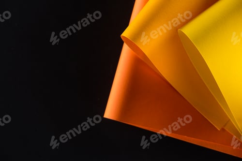 Preview: orange and yellow colored papers isolated on black