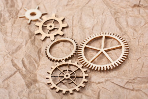 Preview: Small wooden figures of mechanical parts on the wrapped brown background - industrial concept