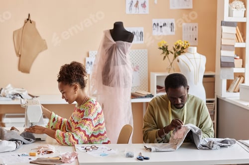 Preview: Two young creative African American designers or stylists sewing new clothes