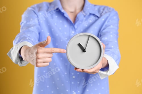 Preview: Young woman holding alarm clock on color background. Time concept