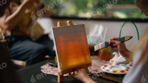 Preview: A person is painting with a palette of colors on a table